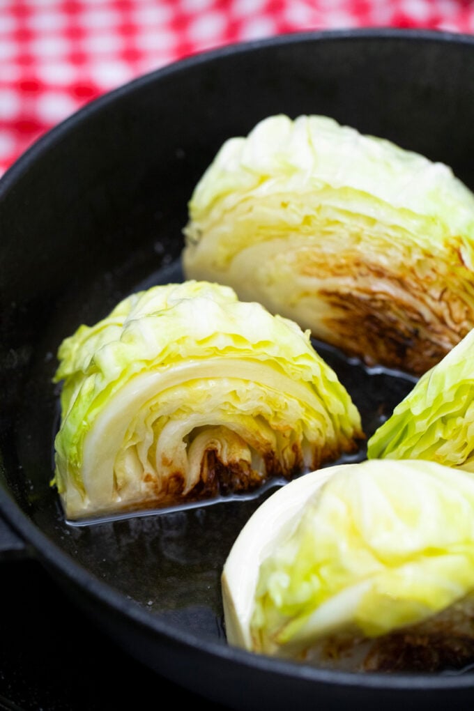 Searing cabbage wedges in a cast iron pan.
