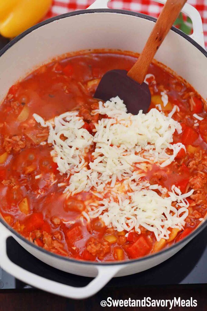 adding white rice to a pot of unstuffed peppers mixture