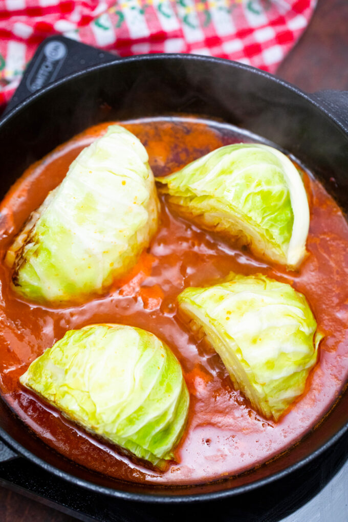 Cooking cabbage wedges in tomato sauce.