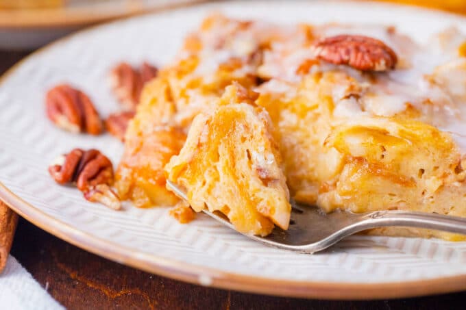 A slice of croissant French toast casserole topped with pecans.