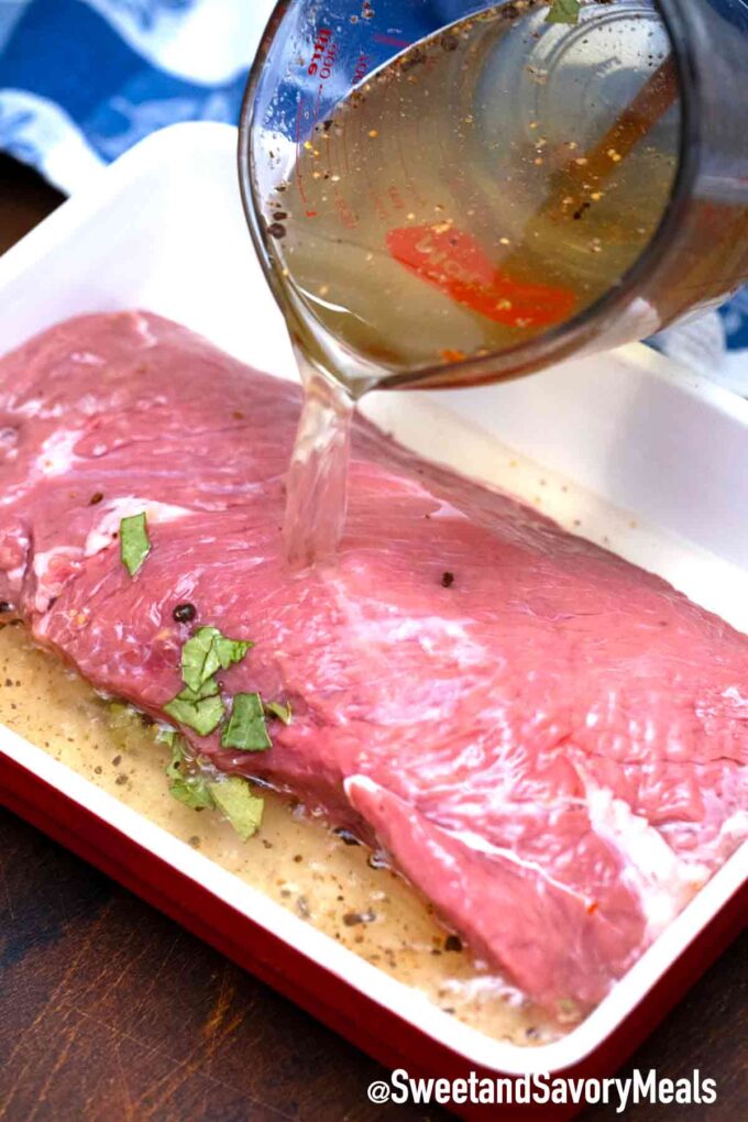 pouring homemade brine over beef to make homemade corned beef