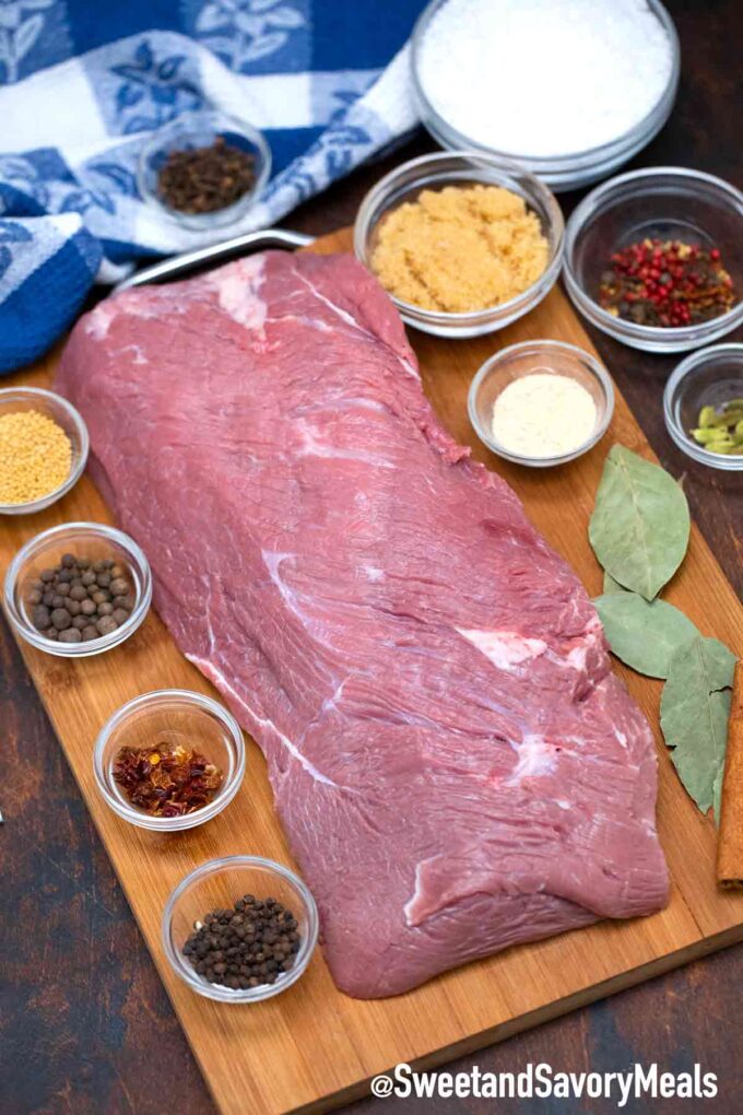 corned beef brine ingredients arranged in bowls on a table next to a piece of meat on a cutting board