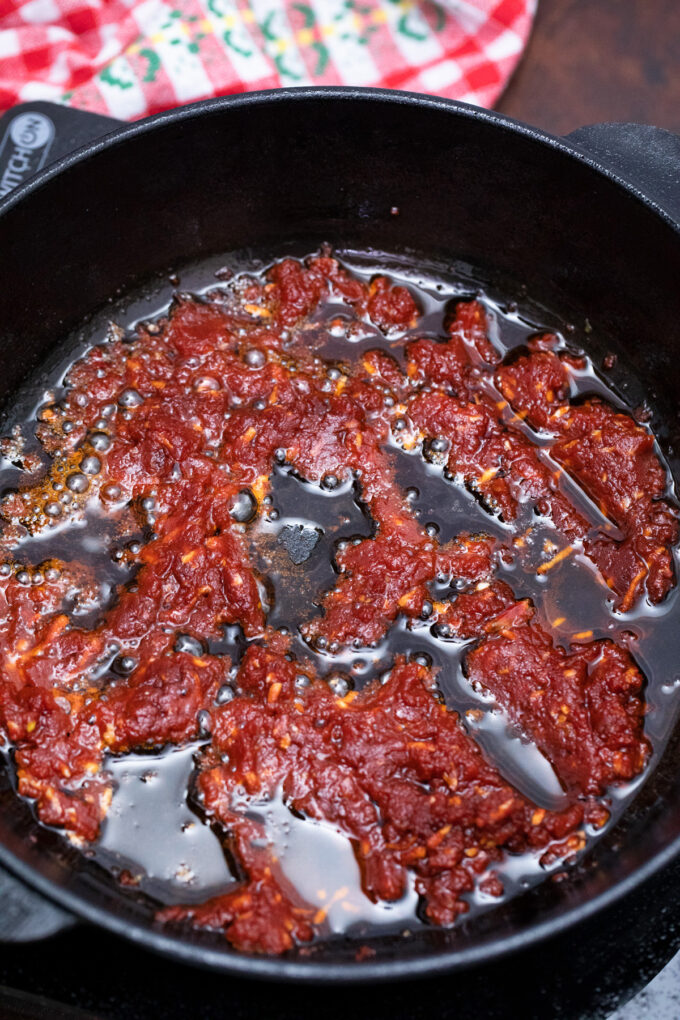 Cooking tomato paste and spices in a cast iron pan.