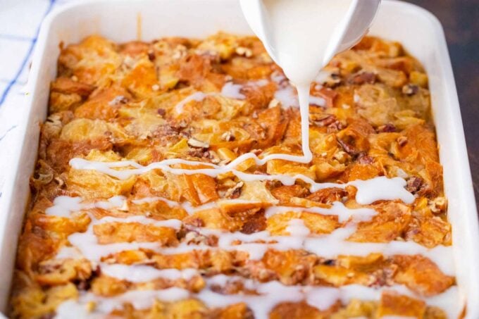 Drizzling glaze over croissant French toast casserole.