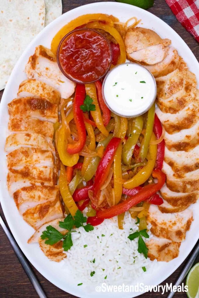 slow cooker chicken fajitas on a plate with rice sour cream and salsa
