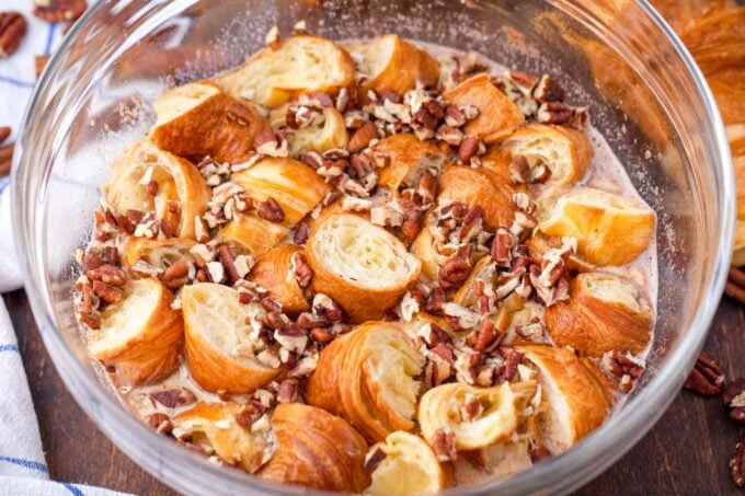 Combining croissant French toast casserole ingredients in a bowl.