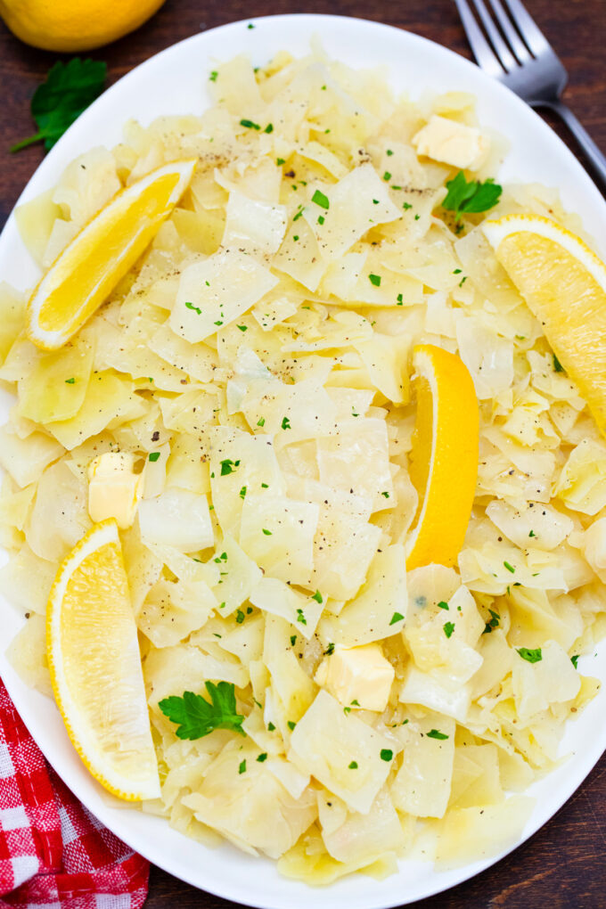 Overhead shot of tender cabbage with lemon wedges.