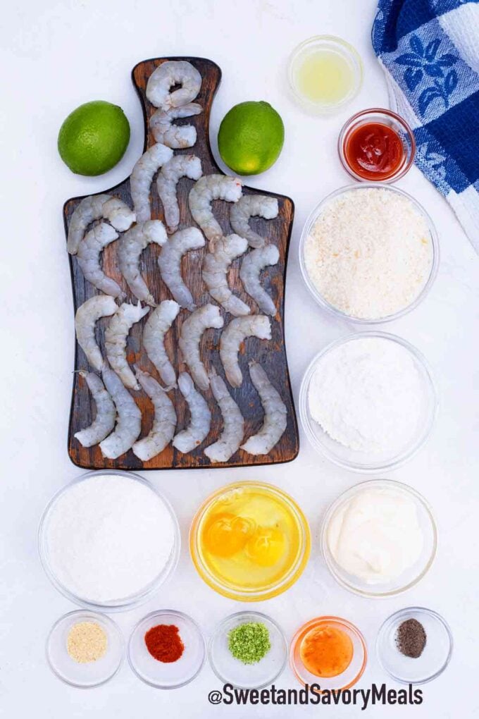 peeled shrimp along with seasoning and sauce ingredients on a wooden board