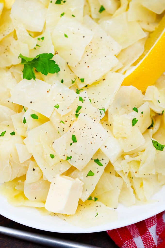 A plate of tender cabbage with lemon wedges.