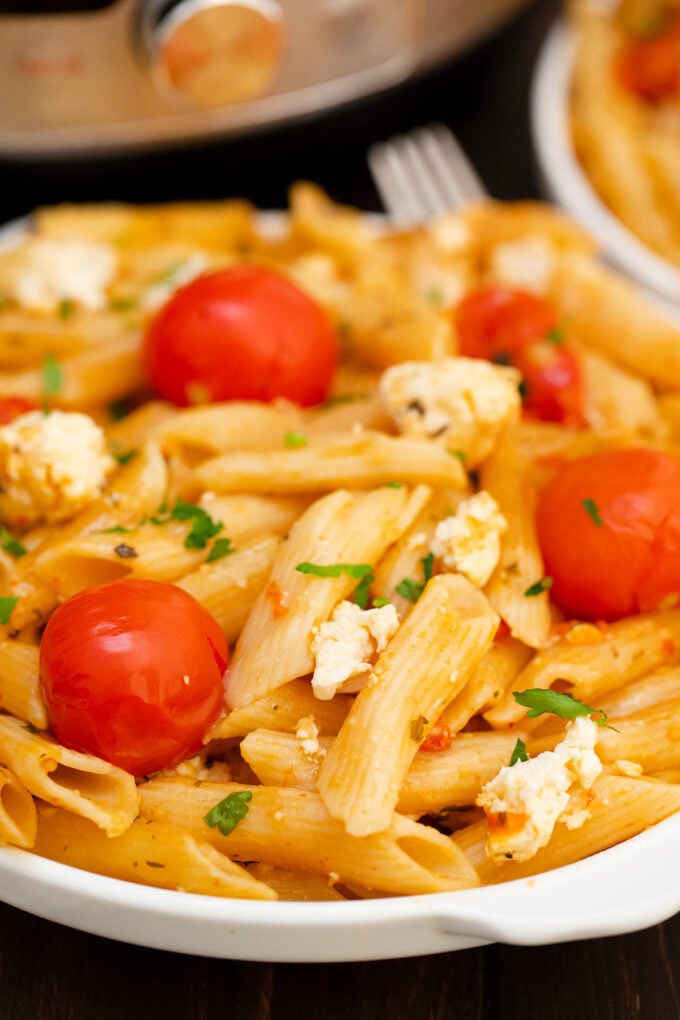 Instant Pot feta pasta with crumbled feta, cherry tomatoes, and basil.