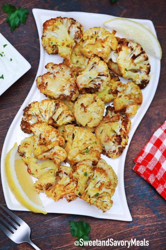 Crispy and seasoned cauliflower with lemon on a white plate