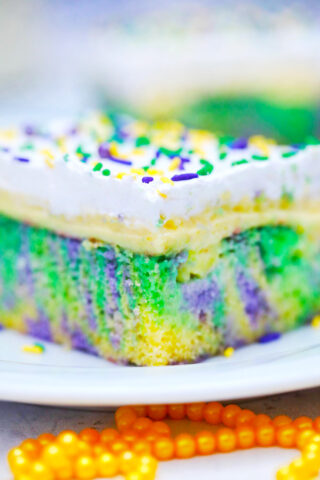 King cake poke cake with layers of pudding and whipped cream.