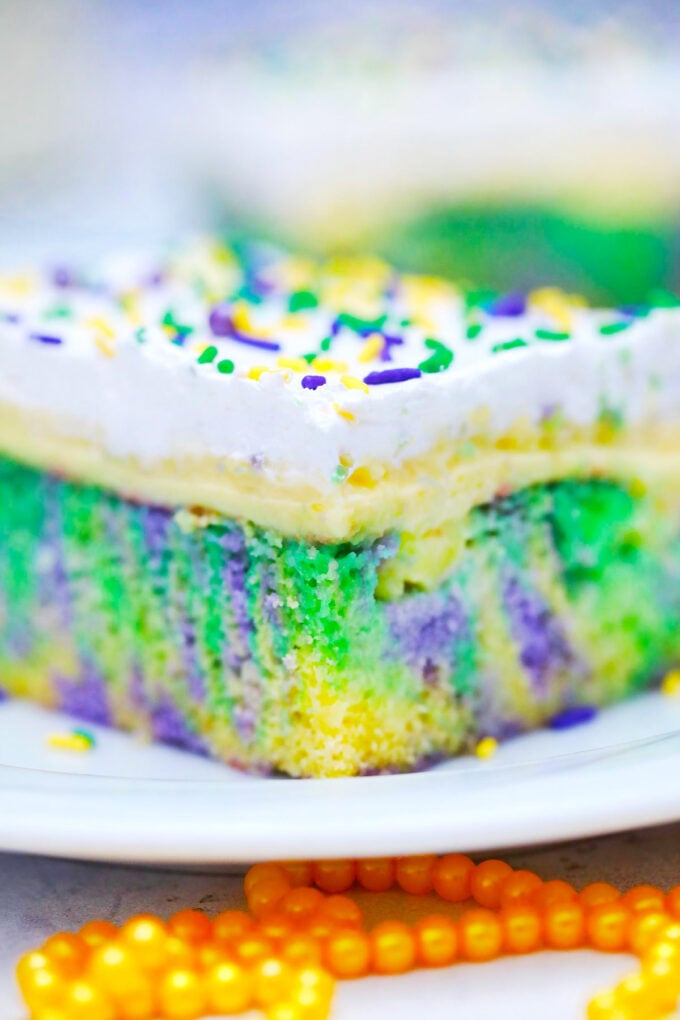 King cake poke cake with layers of pudding and whipped cream.
