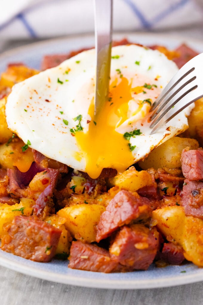 Slicing a runny egg over corned beef hash.