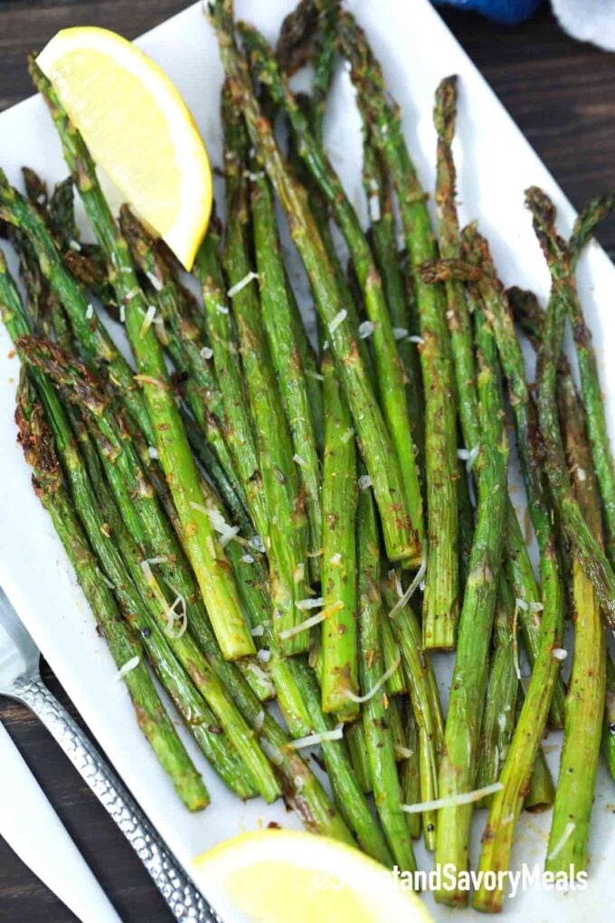 Roasted asparagus on a plate and topped with shredded parmesan and lemon