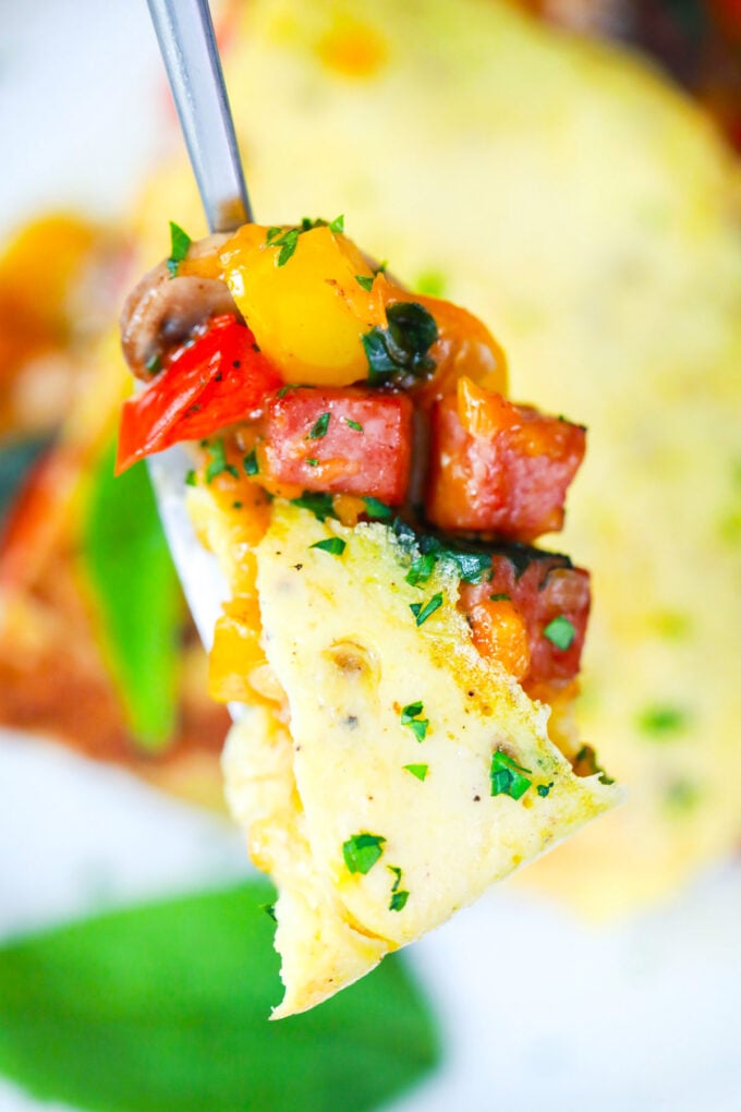 A forkful of fluffy omelet with veggies and ham.