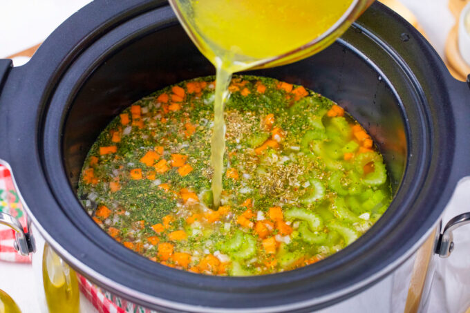 Adding broth and vegetables to crockpot.
