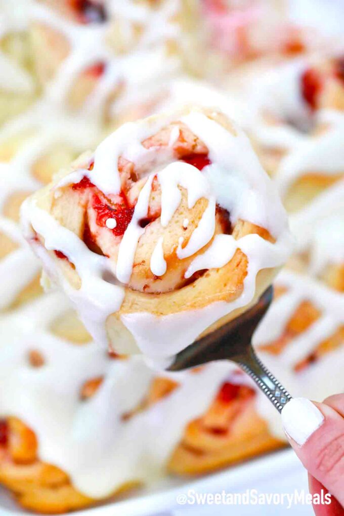 strawberry rolls with cream cheese icing on a serving spatula