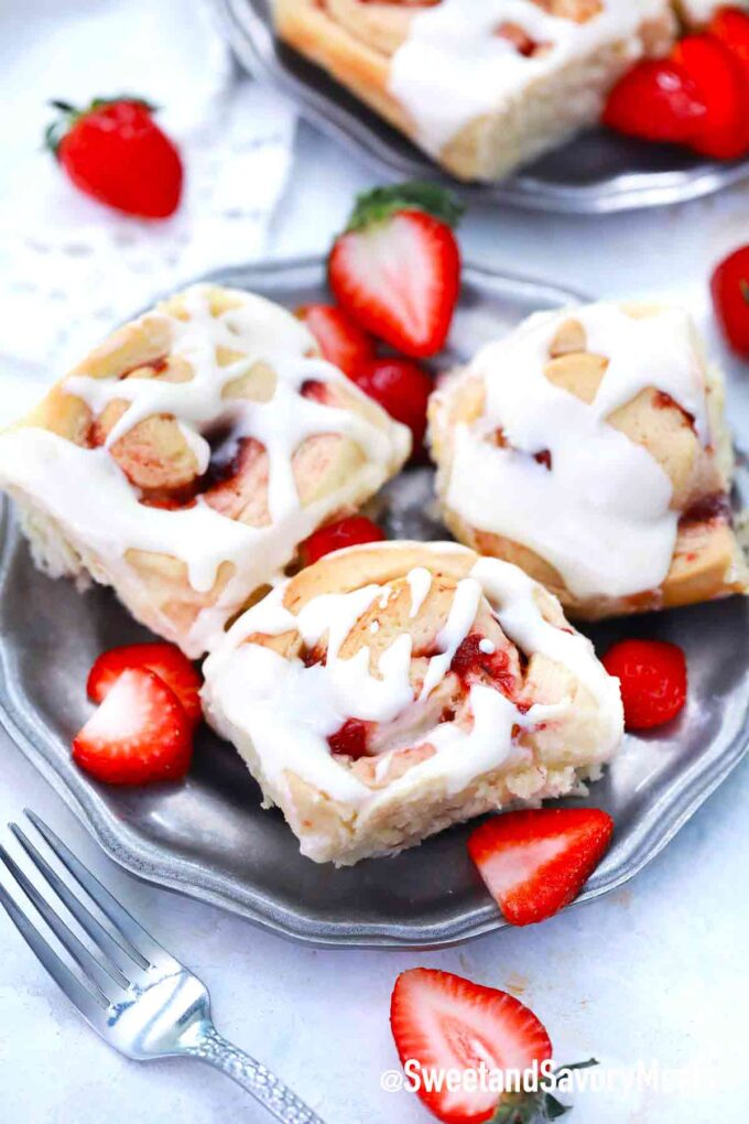 three strawberry rolls with cream cheese frosting on a plate