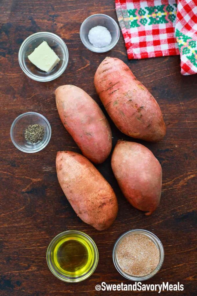 Four medium-sized sweet potatoes and seasoning on a wooden table