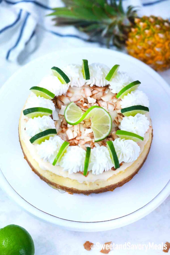 instant pot Pina Colada cheesecake garnished with whipped cream, toasted coconut, and lime slices