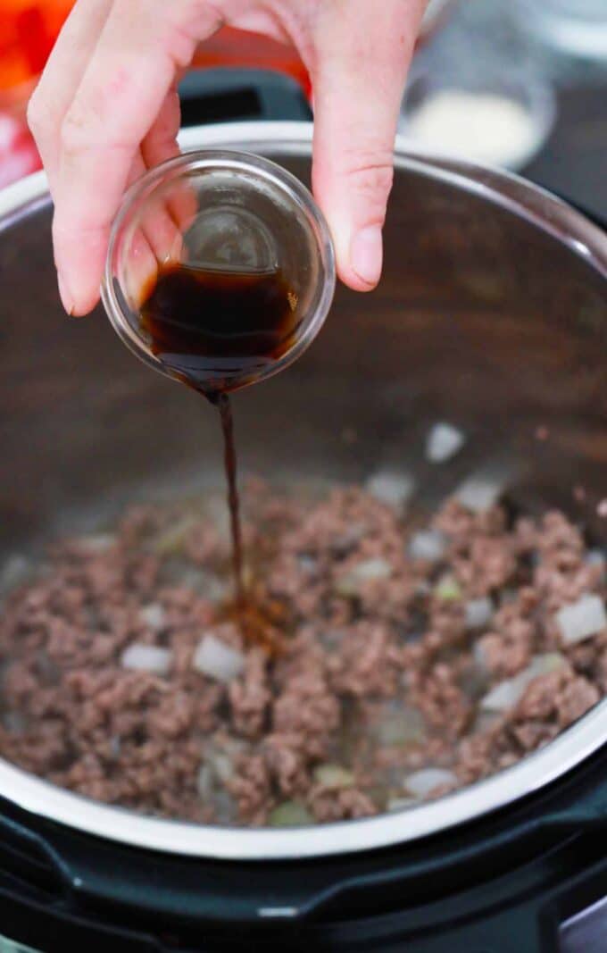 Adding Worcestershire sauce to browned beef in the Instant Pot.