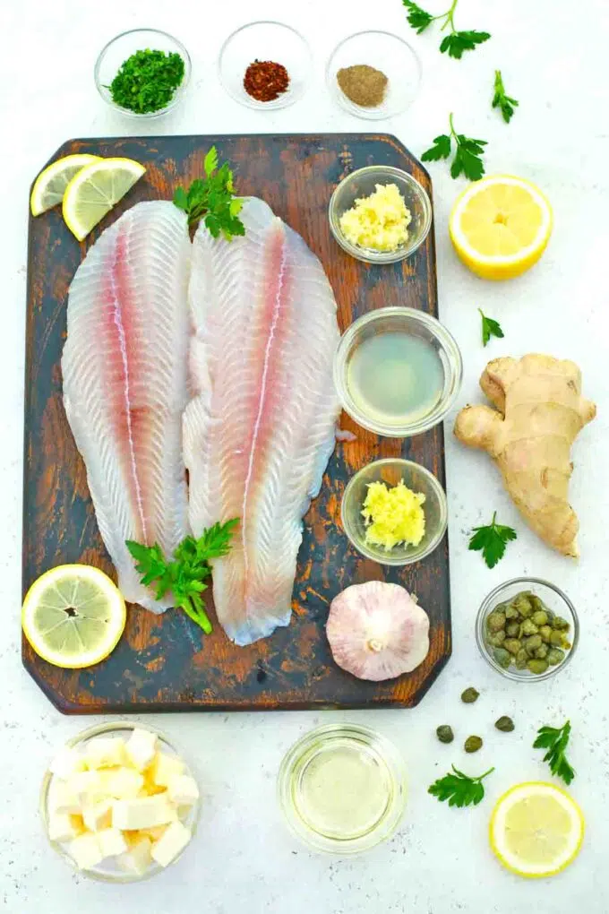 Swai fish fillets on a cutting board and ingredients in bowls