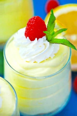 Close shot of creamy lemon mousse topped with whipped cream.