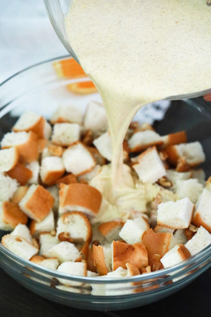 Pouring egg custard over bread pieces.