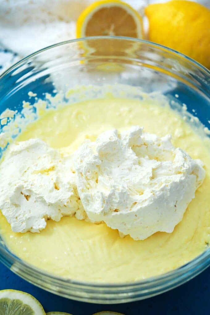Adding whipped cream to a bowl of cream cheese and lemon curd.