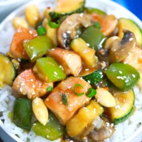 almond chicken with veggies on top of a bowl with rice