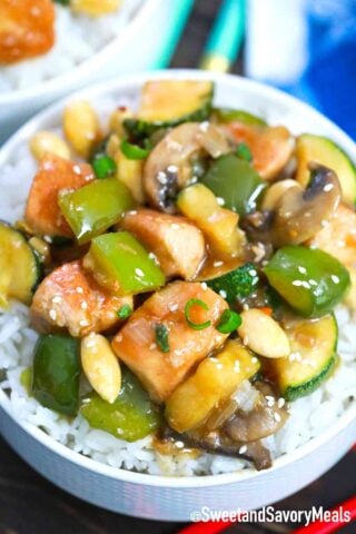 almond chicken with veggies on top of a bowl with rice