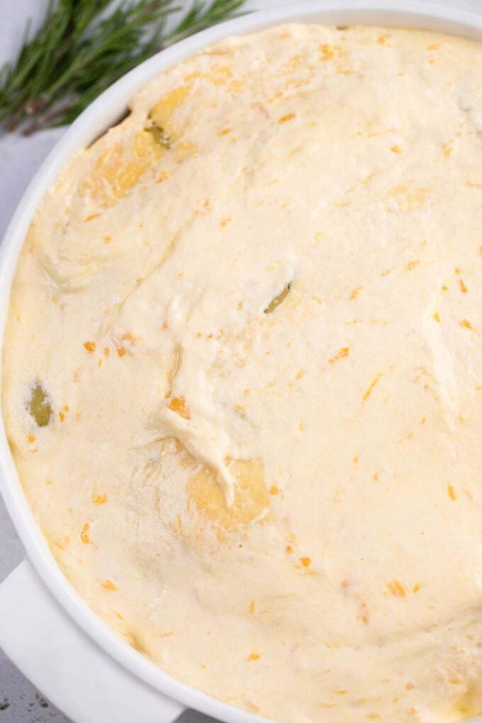 Scalloped potatoes arranged in a baking dish topped with cheese sauce.