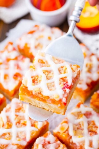 Peach crumb bar on a serving spatula.