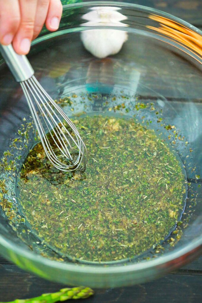 Stirring veggie marinade in a bowl.