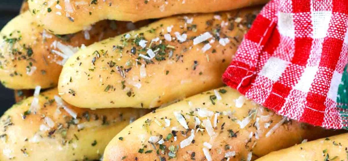 homemade breadsticks covered with a kitchen towel
