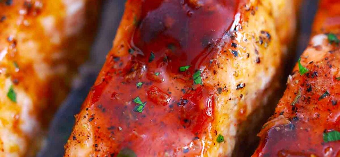 pouring honey garlic sauce on salmon fillets