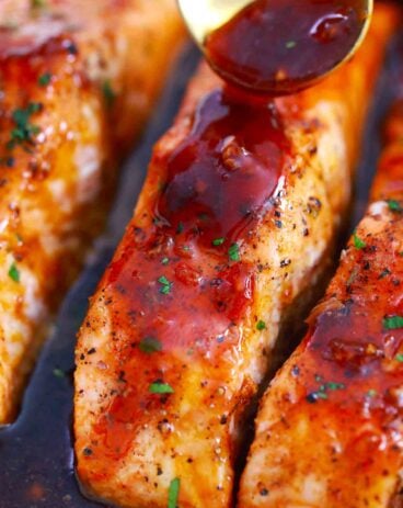pouring honey garlic sauce on salmon fillets