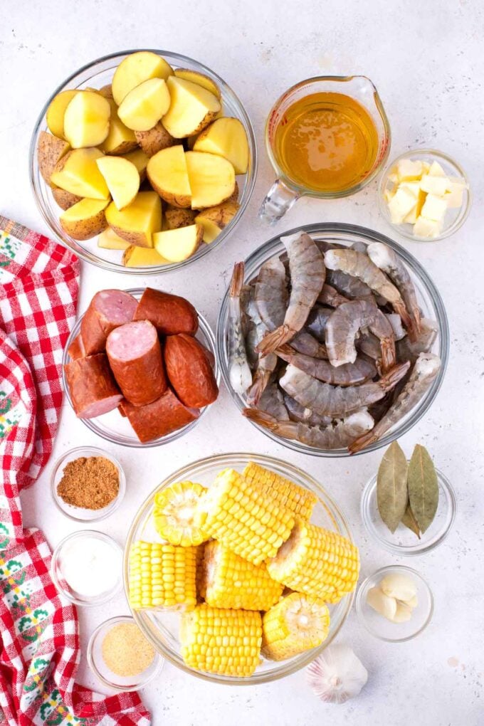 Overhead shot of instant pot shrimp boil ingredients in bowls on a white surafce.