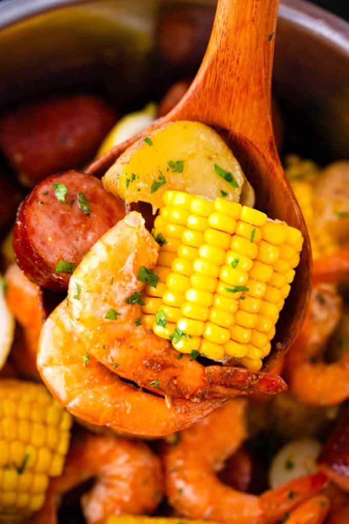 A ladle with shrimp, corn and sausage.