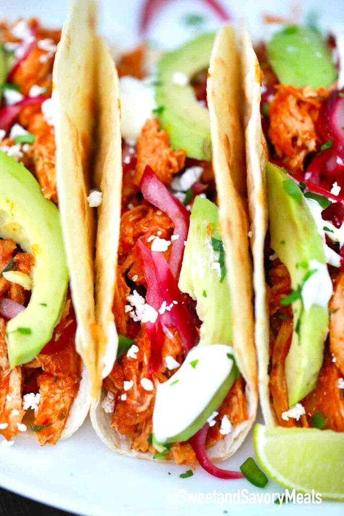 Chicken Tinga tacos with red onions and avocado in a flour tortilla