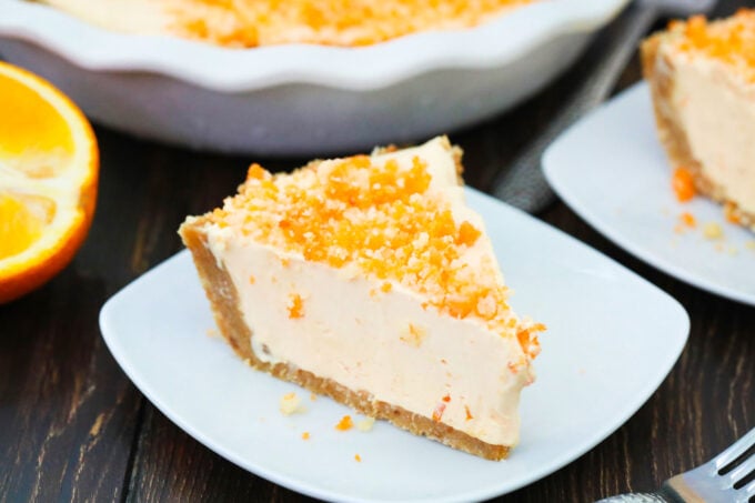 A slice of orange creamsicle freezer pie topped with orange crumbles.
