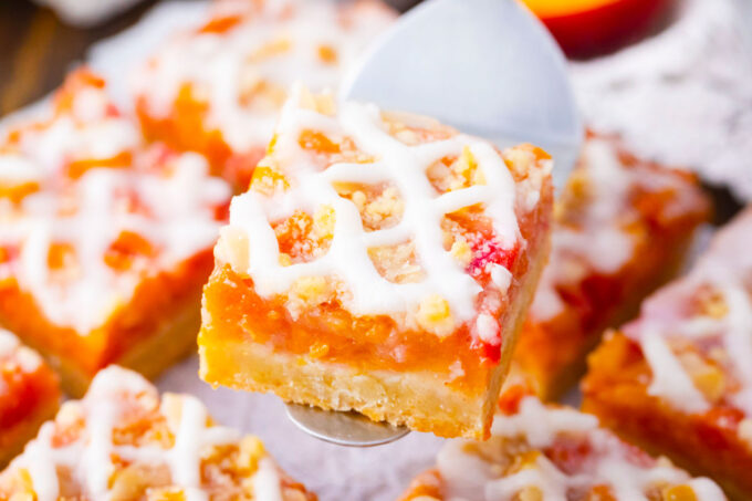Glazed peach crumb bar on a serving spatula.