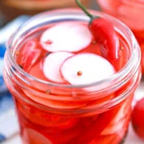 pickled radishes in a jar with a red chili pepper