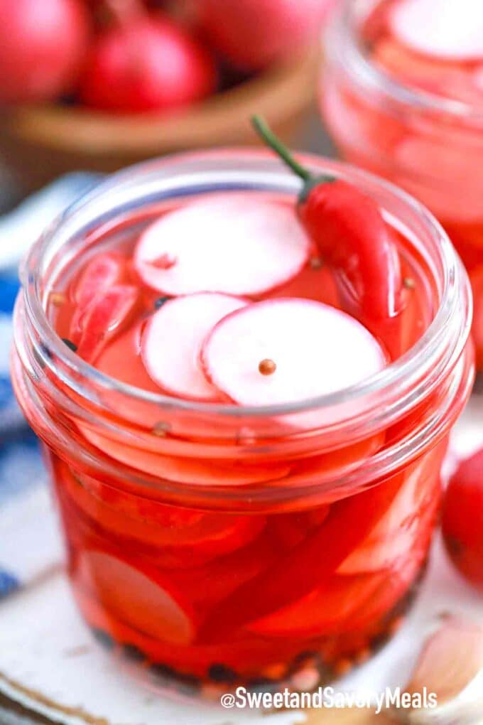 pickled radishes in a jar with a red chili pepper