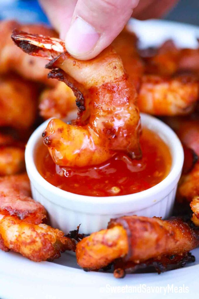 dipping bacon wrapped shrimp in sauce