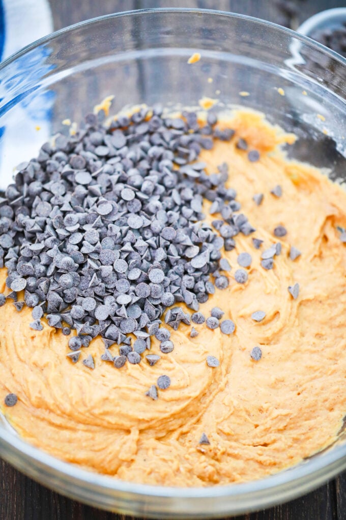 Stirring chocolate chips into pumpkin bread batter.