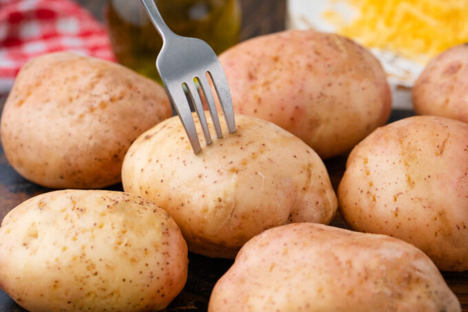 Piercing potatoes with a fork.