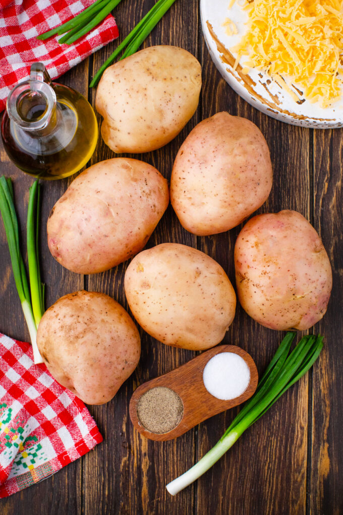 Overhead shot of slow cooker baked potatoes on a wooden table.