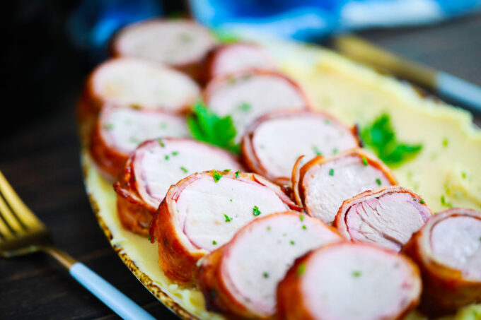 Homemade air fryer bacon wrapped pork tenderloin over mashed potatoes.